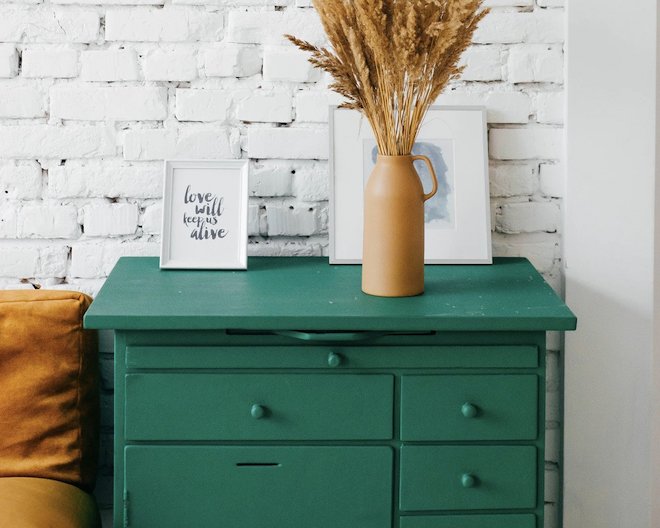 Teal drawers with two frames and a vase on top